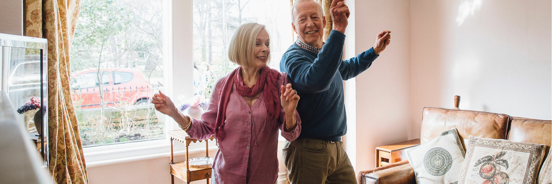 An elderly couple dancing to music in their home