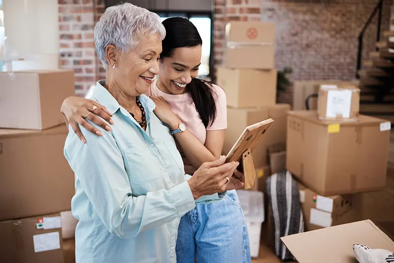 Shot of a senior woman looking at a photograph with her daughter while packing boxes on moving day