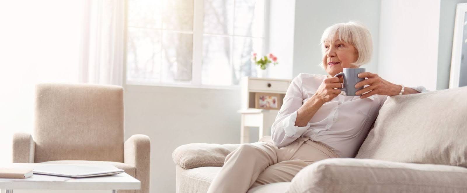 Senior lady sitting on a couch enjoying a coffee